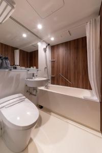 a bathroom with a toilet and a tub and a sink at The Machiya Kamiumeya in Kyoto