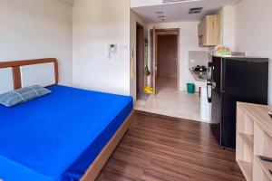 a bedroom with a blue bed and a kitchen at RedLiving Apartemen Puri Orchard - Millenial Room Tower Orange in Jakarta +21 photos
