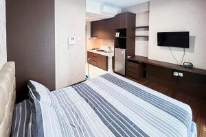 a small room with a bed and a kitchen at RedLiving Apartemen Puri Orchard - Millenial Room Tower Orange in Jakarta
