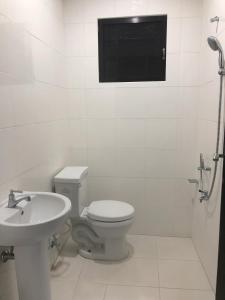 a white bathroom with a toilet and a sink at Hanella's Place in Bacong +28 photos