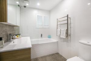 Un baño blanco con bañera y lavabo. en Bliss And Harmony, en Gold Coast 8 fotos más