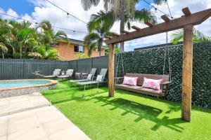 Un patio trasero con un columpio y una piscina. en Bliss And Harmony, en Gold Coast