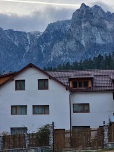 a white house with a fence and mountains in the background at Vila Roxana Busteni in Buşteni