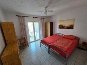 a bedroom with a red bed and a window at Apartment Stula in Omišalj +6 photos