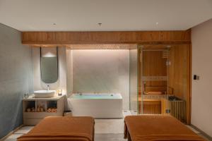 a bathroom with two beds and a tub and a sink at Awaken Da Nang Hotel in Danang