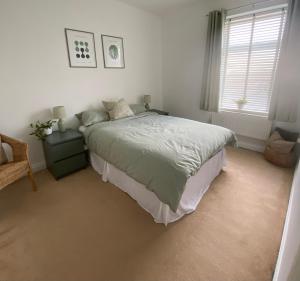 a white bedroom with a bed and a window at Spacious Town House in Aberdare