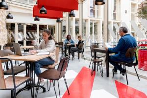 a group of people sitting at tables in a restaurant at MEININGER Hotel Bordeaux Gare Saint-Jean in Bordeaux