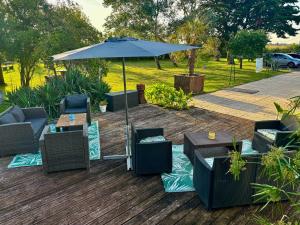 an umbrella and chairs and tables on a deck at Chambres de l enclose in La Barre-de-Monts