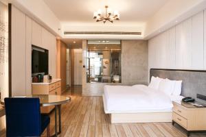 a bedroom with a bed and a table and a television at Wanda Realm Xiamen North Bay in Xiamen