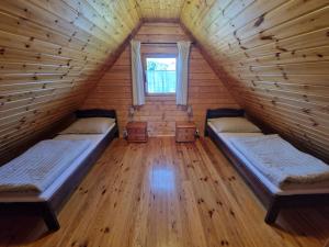 two beds in a wooden room with a window at Anna i Halina in Sztutowo