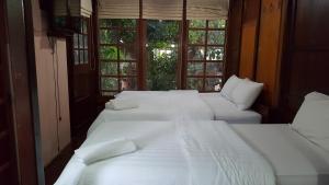 three white beds in a room with windows at Ruean Mai Chai Khlong in Amphawa