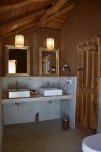 a bathroom with two sinks and two mirrors at Kuwera Eco Lodge in Sigiriya +50 photos