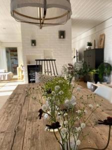 a wooden table with flowers in a living room at Atriumshus for leie under ONS 2024 in Stavanger
