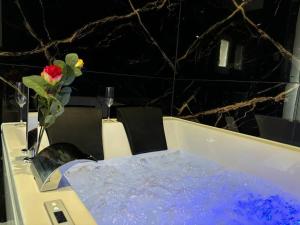 a white table with a vase with a flower on it at Prestige Jacuzzi & Clim, parking - Roanne centre-ville in Roanne +21 photos