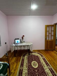 Habitación con mesa y alfombra en el suelo de madera. en House in the Riverside, en İsmayıllı