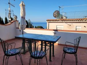 a table and chairs on a balcony with an umbrella at Casa MAIO, attico molto panoramico, in centro storico in Taormina