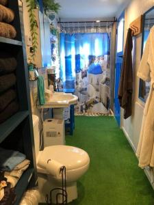a bathroom with a toilet and a sink with a green floor at Fantail at Bluestone Retreat in Leeston