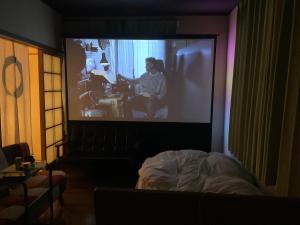 a room with a screen with a woman sitting at a piano at Artful Cats house in Tokyo
