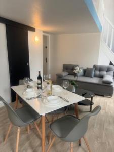 a white table with chairs and wine glasses and a couch at Appartement cozy proche de toutes commodités in Gagny +2 photos