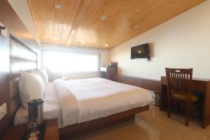 a bedroom with a white bed and a chair at Hotel Mussoorie Heights in Dehradun