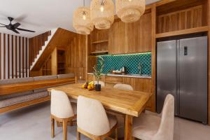 a kitchen with a wooden table and a stainless steel refrigerator at The Arca Villas by GenuineHost in Sanur +54 photos