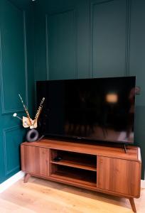 a flat screen tv sitting on top of a wooden entertainment center at L'Élégant, appartement au cœur de la ville in Saumur