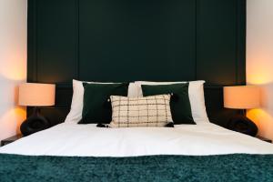 a bedroom with a bed with a green headboard and two lamps at L'Élégant, appartement au cœur de la ville in Saumur
