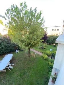 ein Picknicktisch und ein Baum im Garten in der Unterkunft Colibri in Rocquencourt
