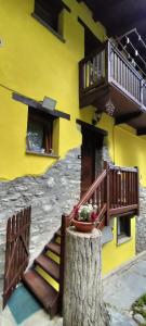 a yellow building with a tree stump with a flower pot on it at Maison du Soleil- CIR VDA Valtournenche n 0204 in Valtournenche