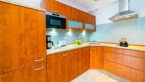 a large kitchen with wooden cabinets and a sink at VacationClub - Leśny Dom 18 Apartament 15 in Karpacz