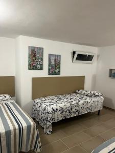 a bedroom with two beds and two paintings on the wall at Perla Bianca in Marina di Lizzano