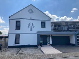 a white house with a garage in a parking lot at Ferienwohnungen Bali in Rust
