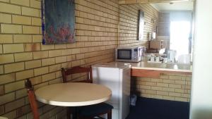 uma pequena cozinha com uma mesa e um micro-ondas em Nambour Central Motel em Nambour