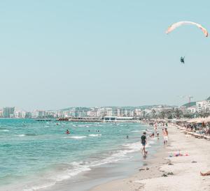 a beach with people in the water and a city at Yacht Hotel in Vlorë