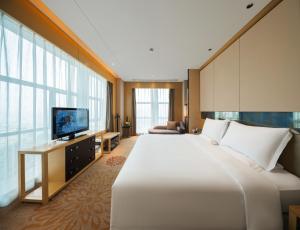 a hotel room with a large bed and a television at Grand Skylight International Hotel Ganzhou Chang Zhen Avenue in Ganzhou