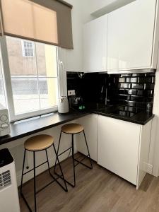 a kitchen with two stools and a black counter top at Stylish City Centre Studio - Grand Central House in Gibraltar +29 photos