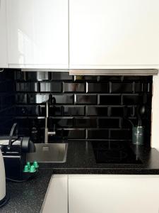 a kitchen with black tile on the wall at Stylish City Centre Studio - Grand Central House in Gibraltar