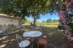een tafel en stoelen in een tuin met bomen bij Gîte de la Cave - Charmant Gîte provençal avec une chambre in Aigues-Mortes