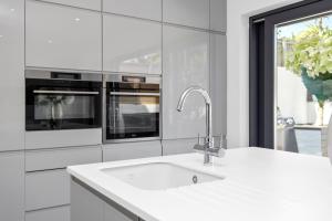 a white kitchen with a sink and two microwaves at Brighton Seaside Retreat in Falmer