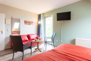 a bedroom with a red bed and a red couch at Strandhaus Malchow in Malchow