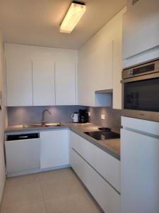 a kitchen with white cabinets and a sink at residentie NAUSICAA in Blankenberge