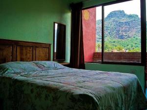 Dormitorio verde con cama y ventana en Posada Paraiso, en Tepoztlán