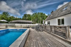 a swimming pool on a wooden deck next to a house at Villa Blanche in Tofta