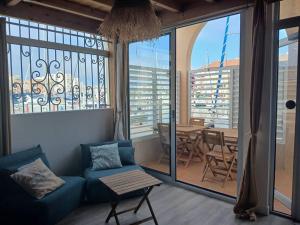 a living room with a couch and a table and windows at Port et Plage Clim & Terrasse in Carnon-Plage