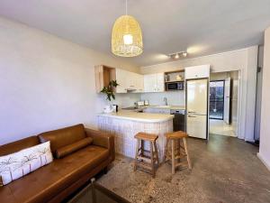 Una sala de estar con un sofá y una cocina. en Chic Beachside 2 Bedroom Apartment in Beautiful Coffs Harbour, en Coffs Harbour