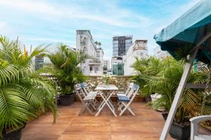 een balkon met een tafel en stoelen en palmbomen bij Woody House Saigon Center in Ho Chi Minh-stad