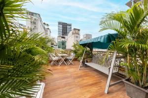 a balcony with tables and chairs and palm trees at Woody House Saigon Center in Ho Chi Minh City