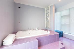 a bathroom with a white tub and pink tiles at Città Studi Suites - Top Collection in Milan