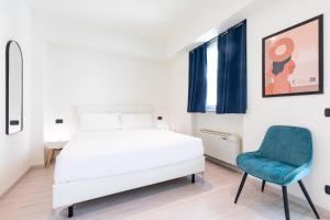 a bedroom with a white bed and a blue chair at Città Studi Suites - Top Collection in Milan