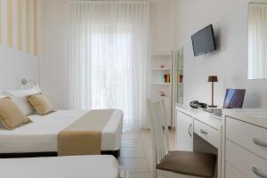 a white bedroom with a bed and a television at Hotel Aqua in Cattolica